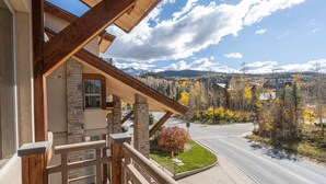 A wooden balcony with stone pillars, overlooking a road and autumn-colored trees with a mountainous backdrop. - Gorgeous Granita Ski in/Ski out (Telluride)