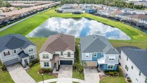 A residential area with houses, a central pond, and a well-maintained lawn. - Games Room | Kids Bedrooms | Screened Pool with Water Views (Kissimmee)