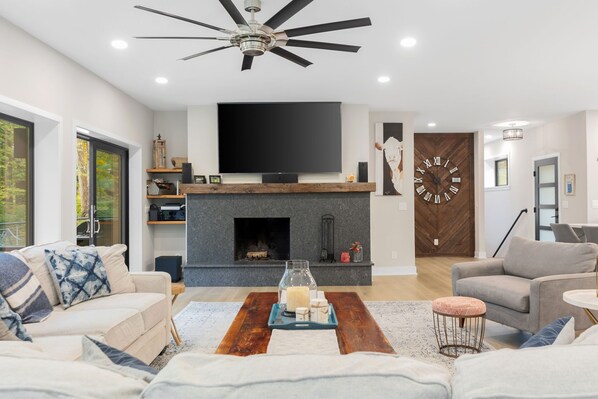 Un salon moderne avec une cheminée, une grande horloge et un ventilateur de plafond.