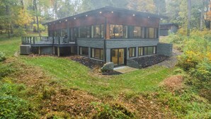 Una casa moderna de dos pisos con base de piedra, ventanas grandes y una terraza.
