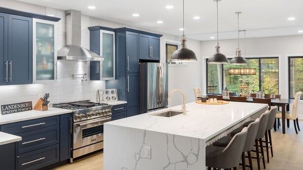 Una cocina moderna con armarios azules, electrodomésticos de acero inoxidable y una isla grande con taburetes de bar.