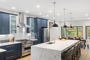 Une cuisine moderne avec des meubles bleus, des appareils en acier inoxydable et un grand îlot central doté de tabourets de bar.