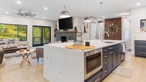 Una cocina moderna con una isla grande, horno integrado y un reloj de pared de gran tamaño.