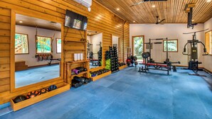 A gym with wooden walls, ceiling fans, and exercise equipment.
