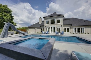 A two-story house with a swimming pool, a slide, and outdoor seating.