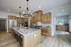 A spacious kitchen with wooden cabinets, a central island, and a chandelier.