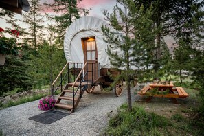 A rustic tent with a wooden staircase leading to a door, surrounded by trees and a picnic table. - North Haven Campground (Bonners Ferry)