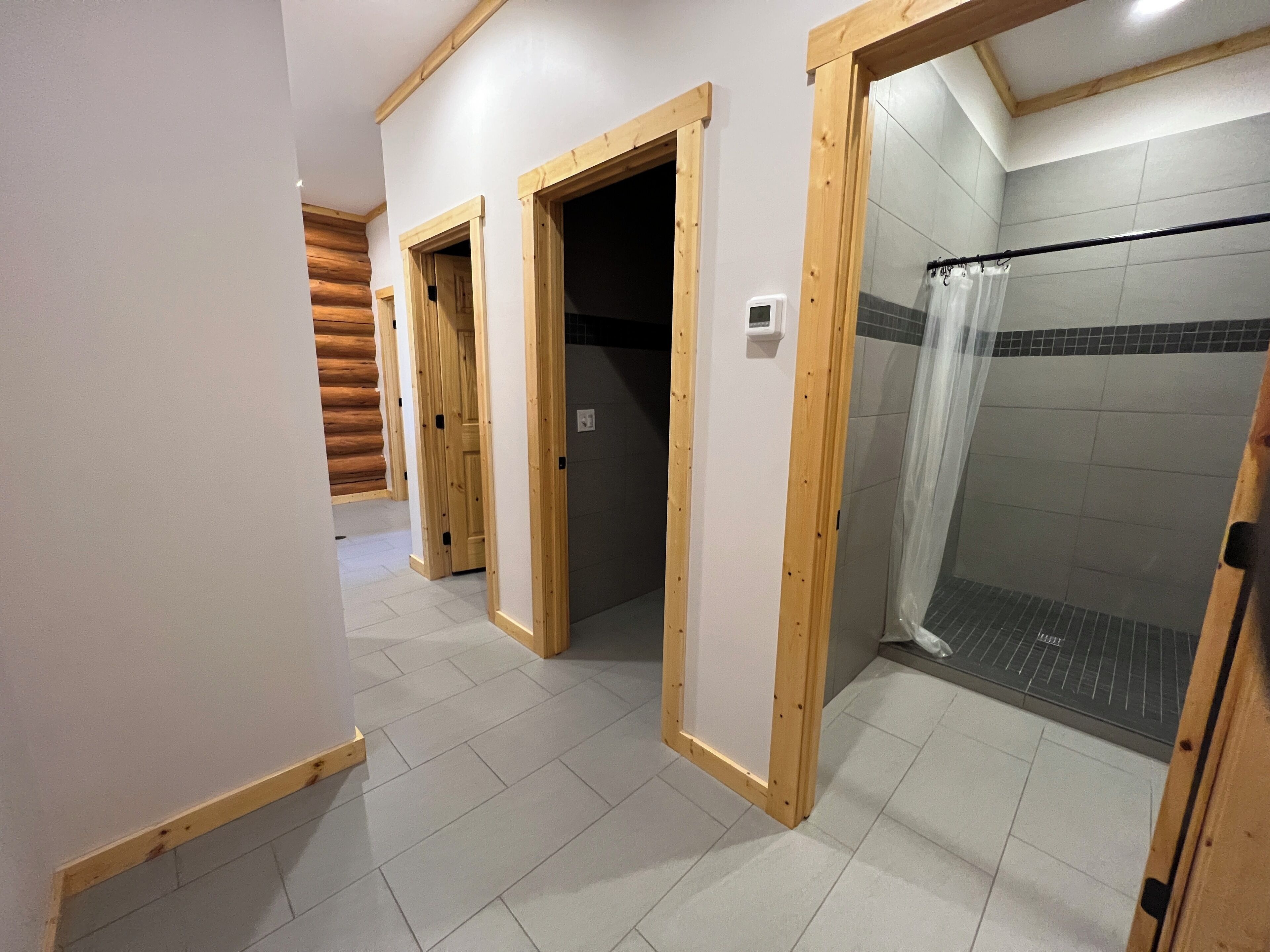 A bathroom with wooden door frames, a shower area with a glass door, and a tiled floor.