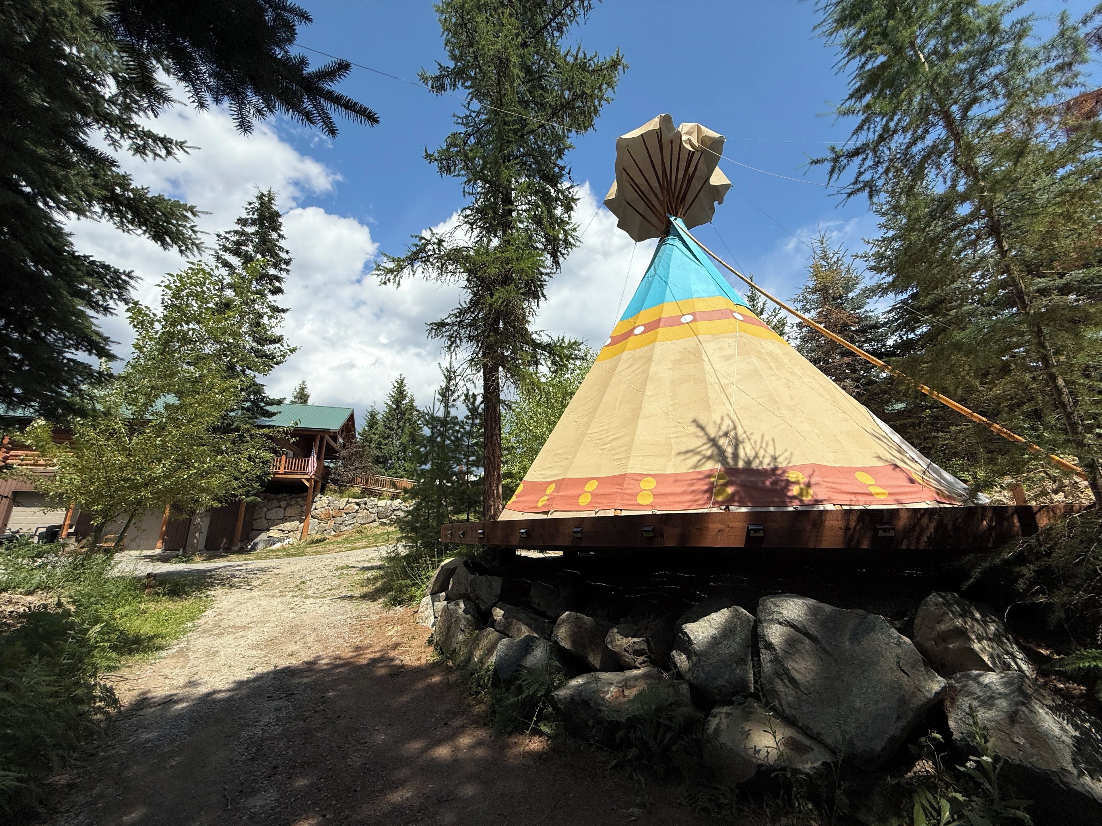 A conical structure with a colorful top, surrounded by trees and a stone pathway.