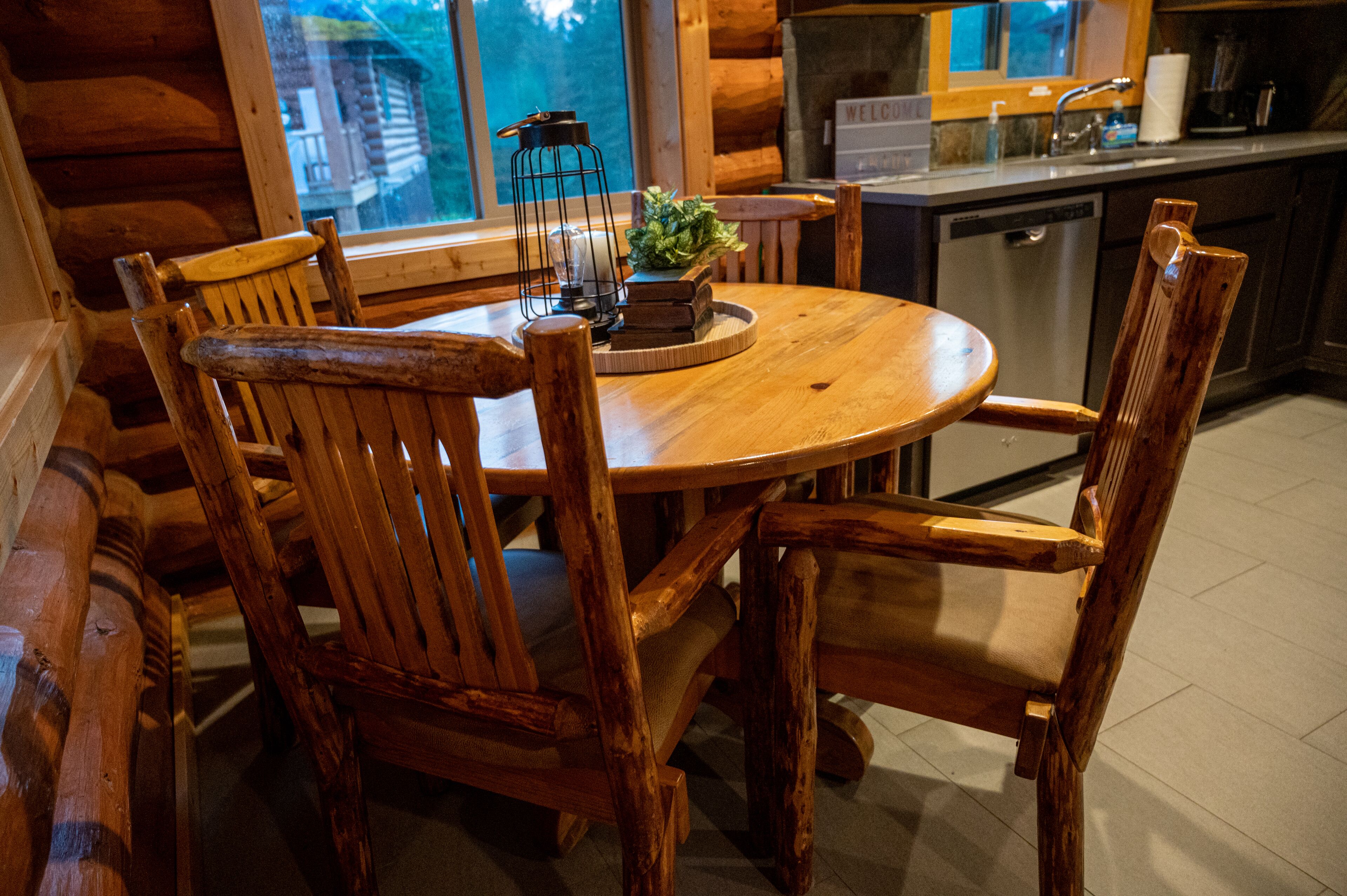 A wooden dining table with chairs, a candle, and a small plant in a wooden bowl.