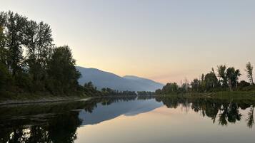 Un río tranquilo con reflejos de árboles y montañas en el agua.