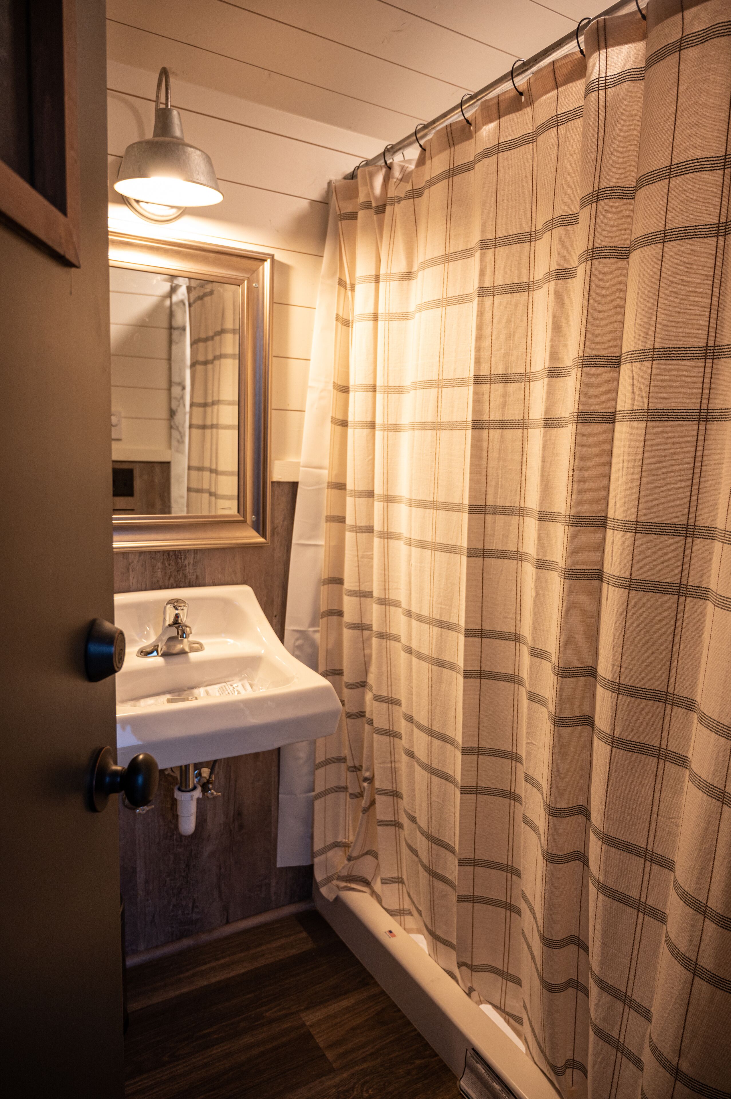 Une salle de bain avec un lavabo, un miroir et un rideau de douche.