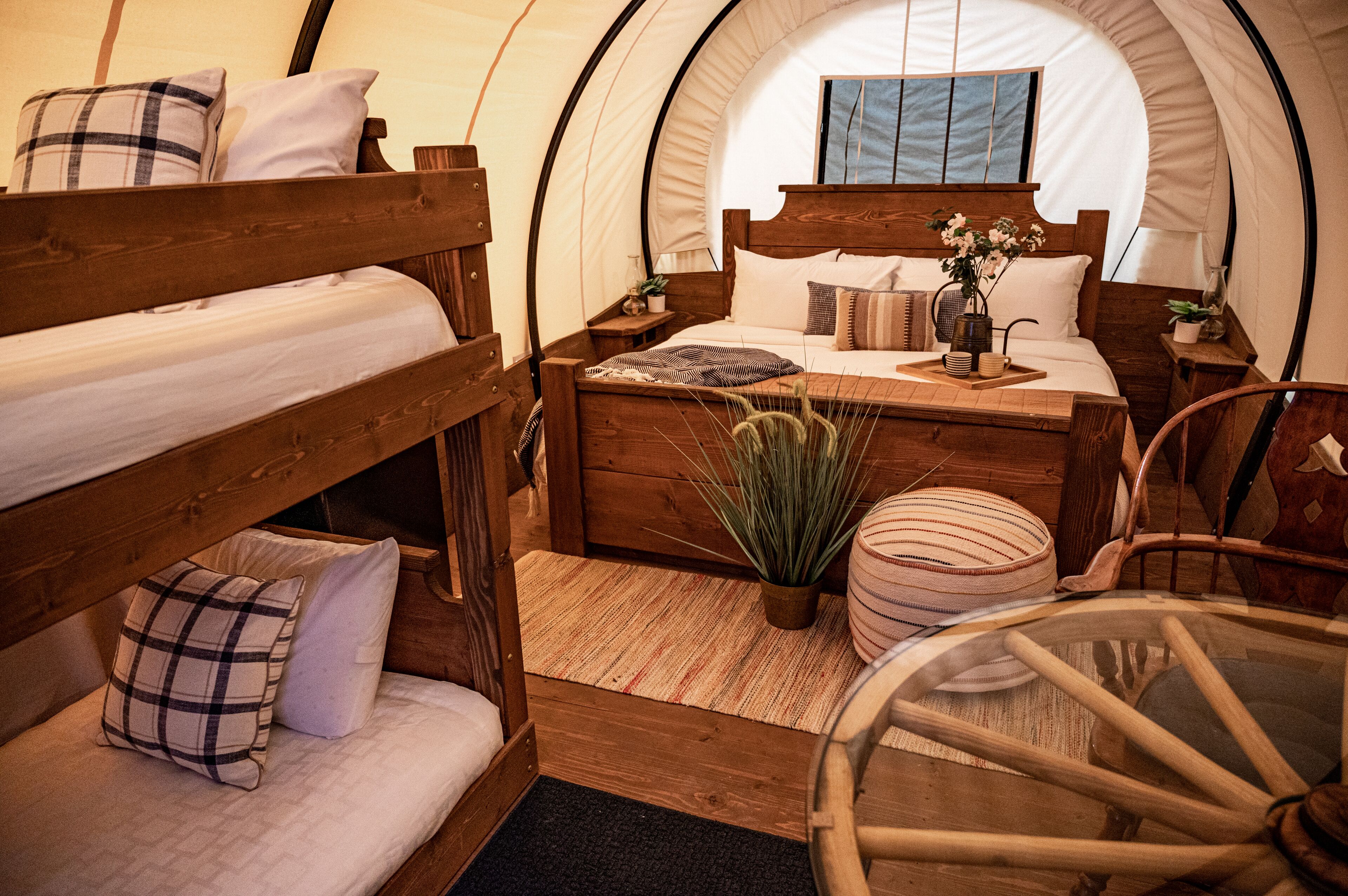 A cozy, circular tent-style room with a wooden bed, a small table, and a chair.