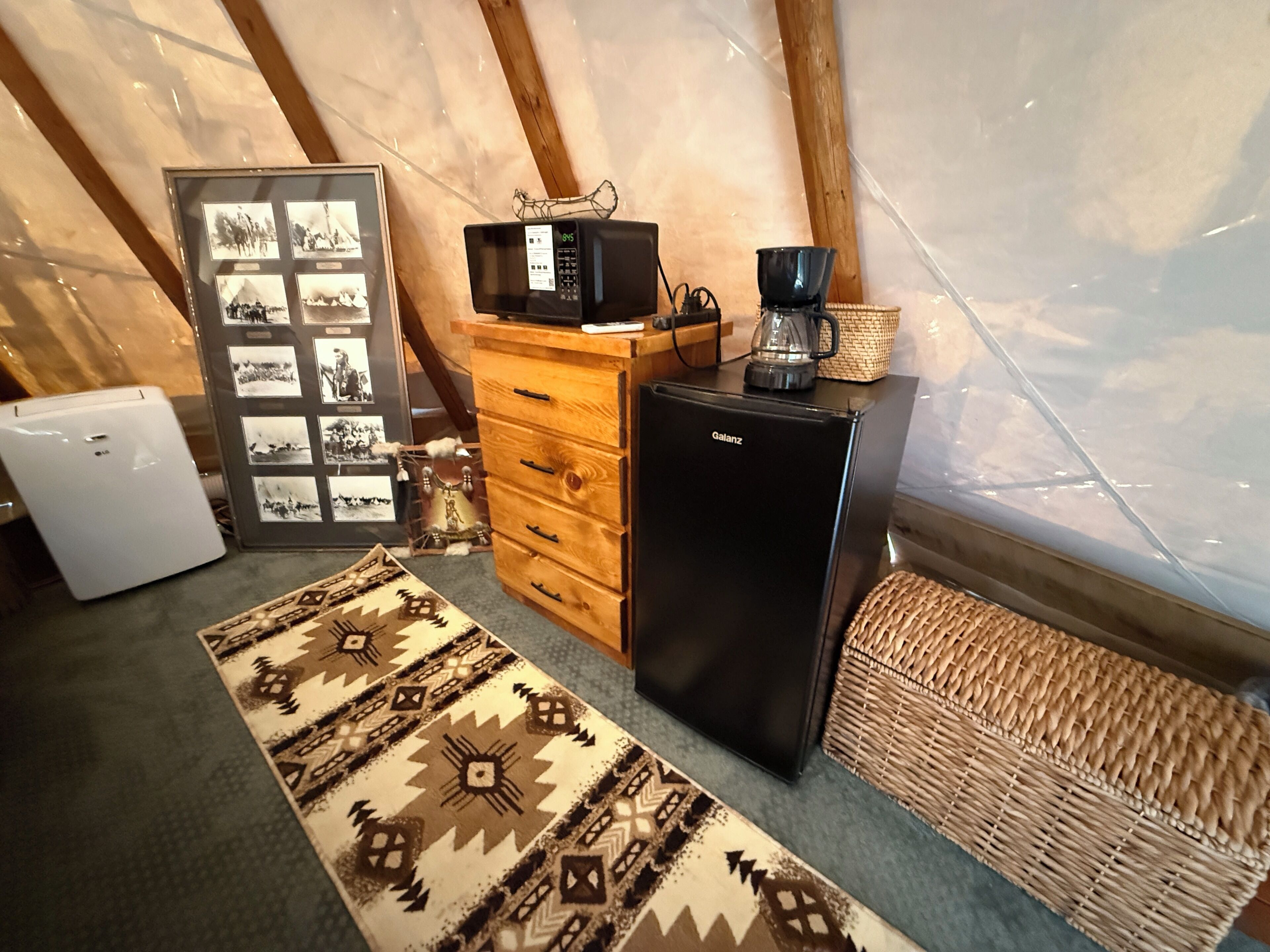 A compact kitchenette with a refrigerator, microwave, coffee maker, and a small cabinet.
