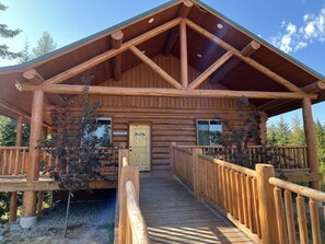 A log cabin with a covered porch and a private bathhouse. - North Haven Campground (Bonners Ferry)