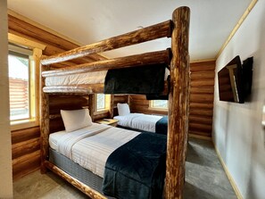 A cabin-style room with a bunk bed, wooden walls, a window, and a flat-screen TV mounted on the wall. - North Haven Campground (Bonners Ferry)