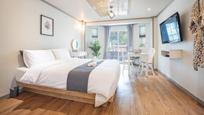 A hotel room with a large bed, a desk with chairs, a TV, and a window with curtains. - Gyeongju Papaya Aegyeondongban Pension (Gyeongju)
