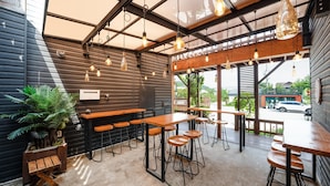 A modern bar area with wooden tables and stools, pendant lighting, and a view of the street. - Gyeongju Papaya Aegyeondongban Pension (Gyeongju)
