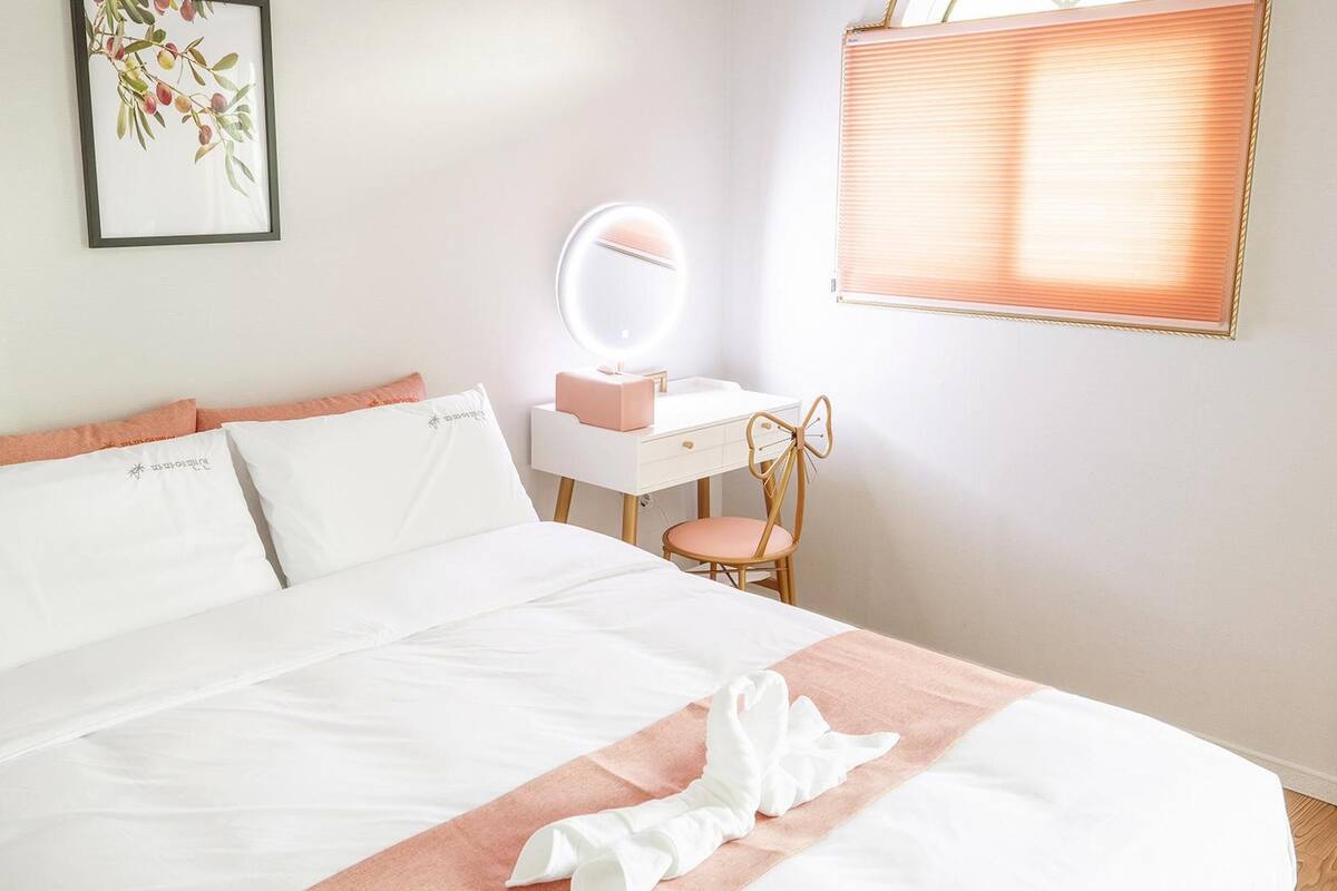 A neatly made bed with white linens and peach-colored pillows.
