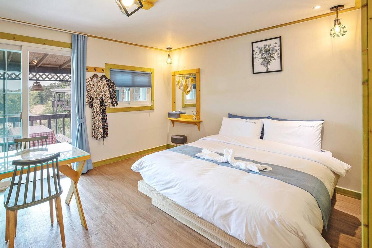 A hotel room with a bed, a table with chairs, a balcony, and a view of the outside.