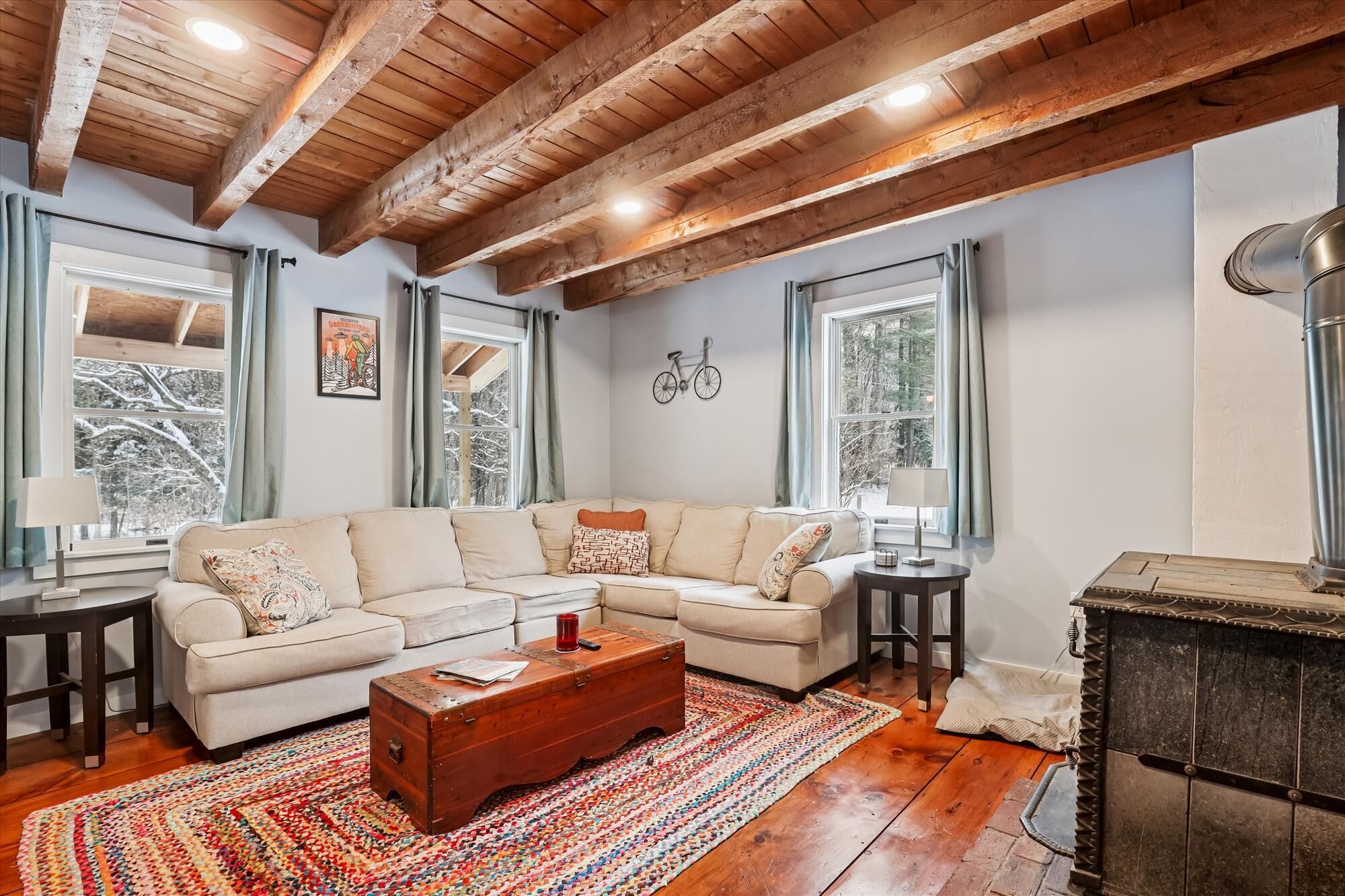 Un salon chaleureux avec un plafond en bois, un canapé d’angle beige, une commode en bois et une cheminée.