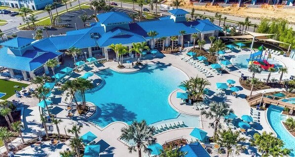 Un complexe hôtelier doté d’une grande piscine centrale, de nombreux espaces de détente et d’un bâtiment remarquable avec un toit bleu.