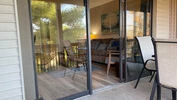 A glass door leading to a balcony with a dining table, chairs, and a sofa.