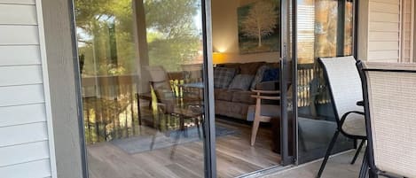 A glass door leading to a balcony with a dining table, chairs, and a sofa.
