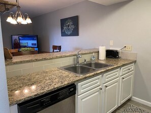 A kitchen with granite countertops, white cabinetry, a double sink, and a dishwasher. - Amazing Walk In Retreat Indoor Pool (Branson)