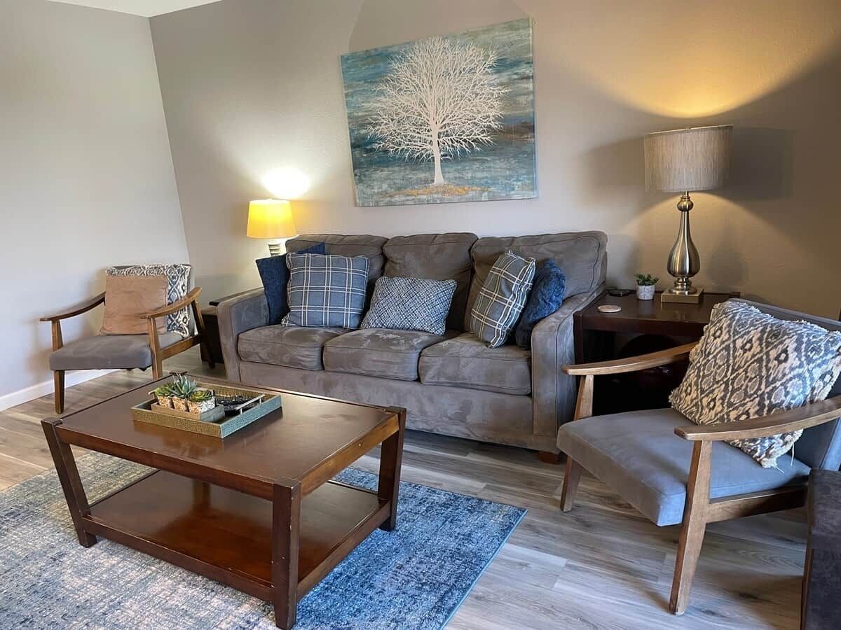 A living room with a sofa, two armchairs, a coffee table, and a lamp.