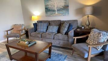 A living room with a sofa, two armchairs, a coffee table, and a lamp.