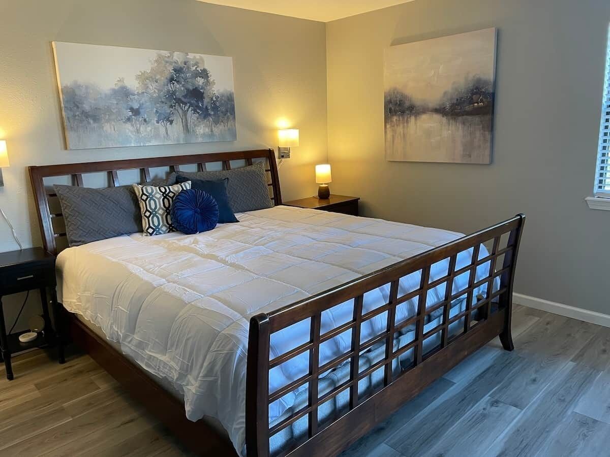 A bedroom with a large bed, two bedside tables, and wall-mounted lamps.