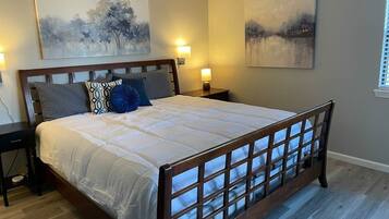 A bedroom with a large bed, two bedside tables, and wall-mounted lamps.