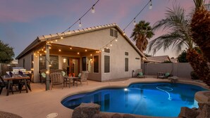 Una casa amb piscina, mobiliari exterior i llums penjants.
