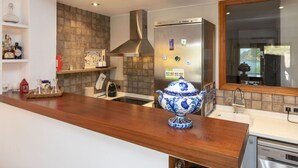 Uma cozinha moderna com bancada de madeira, eletrodomésticos de aço inoxidável e um vaso decorativo azul e branco.