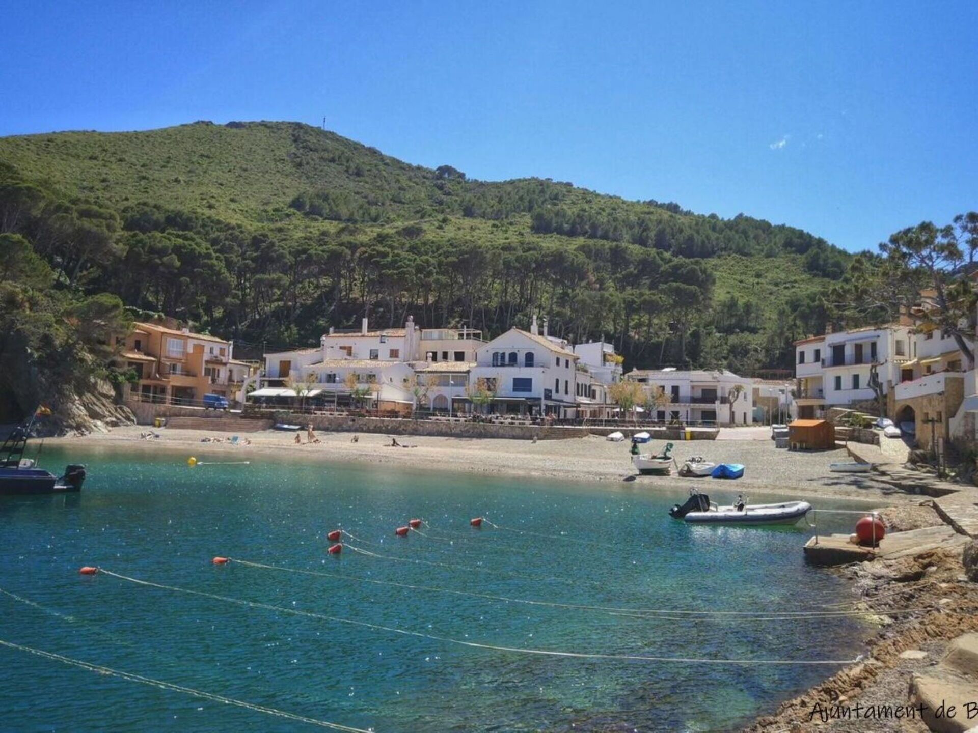 Un pueblo costero con edificios a lo largo de la playa y un mar azul transparente.