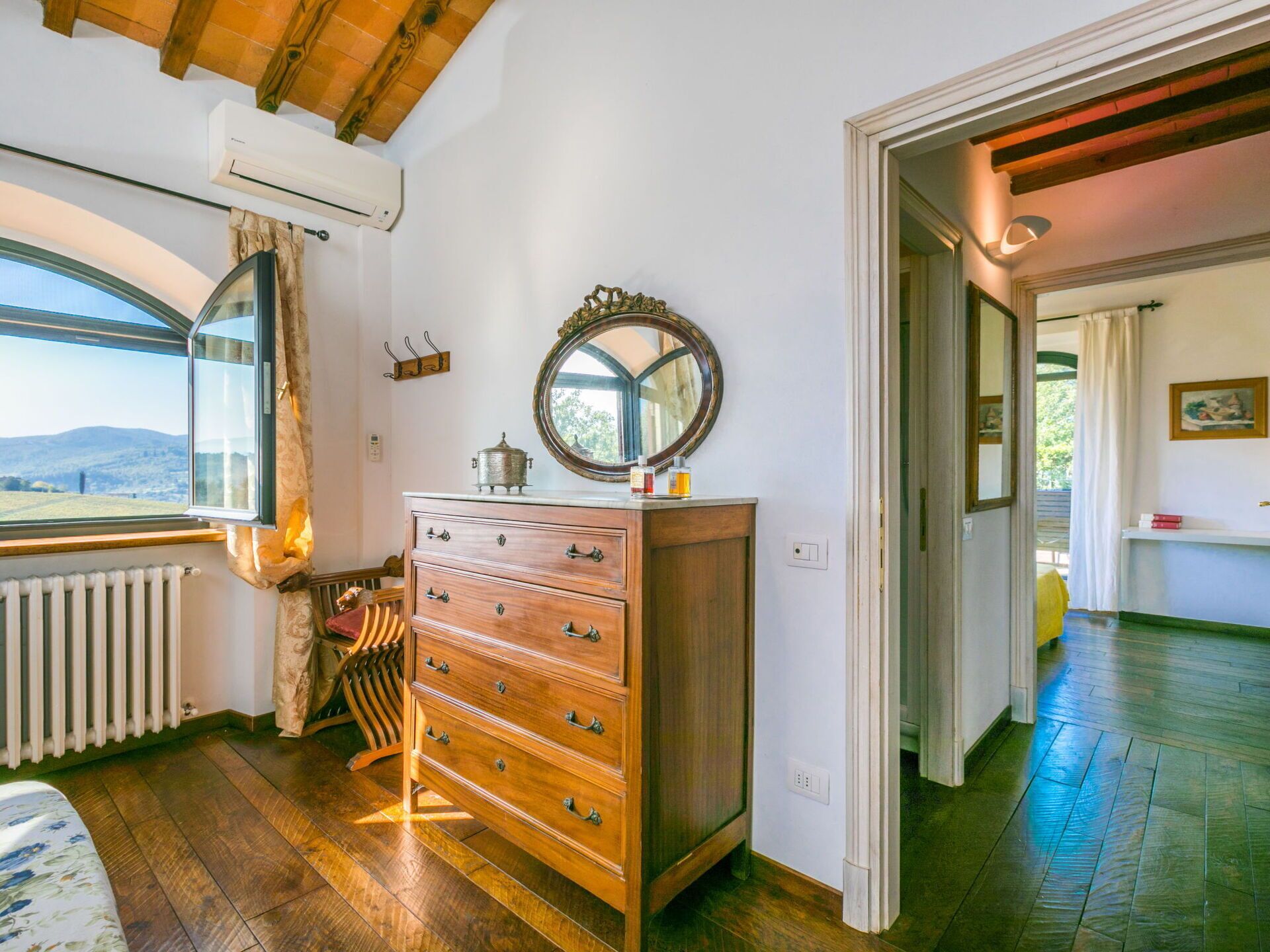 Ein Zimmer mit einem Holzkapuzenkleidungsstück, einem Spiegel und einem Fenster mit Blick ins Freie.