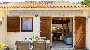 A property with a patio area, a dining table set for two, and a kitchen visible through an open door.