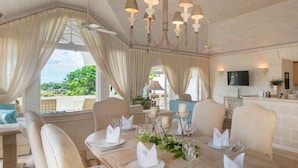 A dining area with a table set for a meal, a kitchen area with wooden cabinets, and a television mounted on the wall. - Forest Hills 23 | Beach View - Located in  Wonderful Saint James with House Cleaning Included (Saint James)