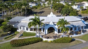 A large, white building with a central archway, surrounded by palm trees and a well-maintained lawn. - Forest Hills 23 | Beach View - Located in  Wonderful Saint James with House Cleaning Included (Saint James)