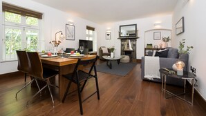 Een moderne woonkamer met een eethoek, een bank, een open haard en een salontafel.