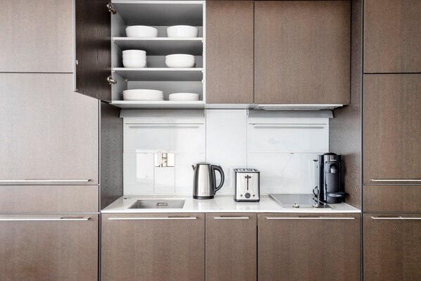 Una cocina moderna con armarios de madera, una tetera de acero inoxidable, un tostador y una cafetera sobre la encimera.
