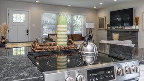 A modern kitchen with a built-in stove, a dining area with a glass-top table, and a living room with a fireplace. - Great Location / Keeneland / Rupp / Fenced Yard / Games (Lexington)