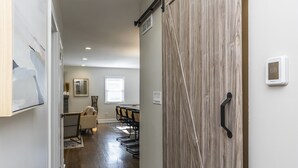 A hallway leading to a dining area with a wooden door and a thermostat on the wall. - Great Location / Keeneland / Rupp / Fenced Yard / Games (Lexington)