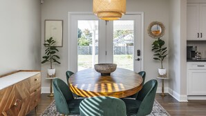 A dining area with a round table, green upholstered chairs, a central bowl, and a hanging light fixture. - Great Location / Keeneland / Rupp / Fenced Yard / Games (Lexington)