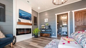 A modern living room with a fireplace, a sofa, a bench, and a dining area with a table and chairs.