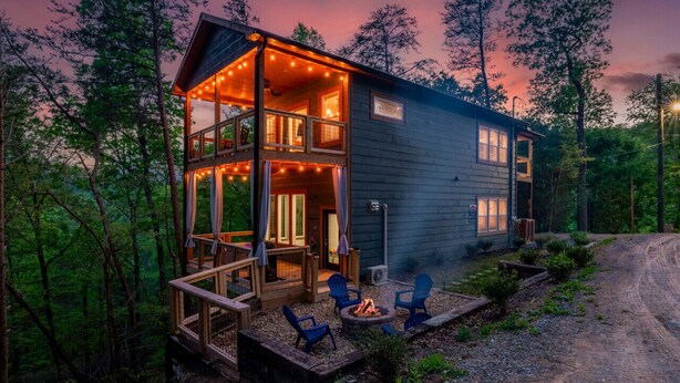 A cabin with a deck, outdoor seating, and a fire pit.