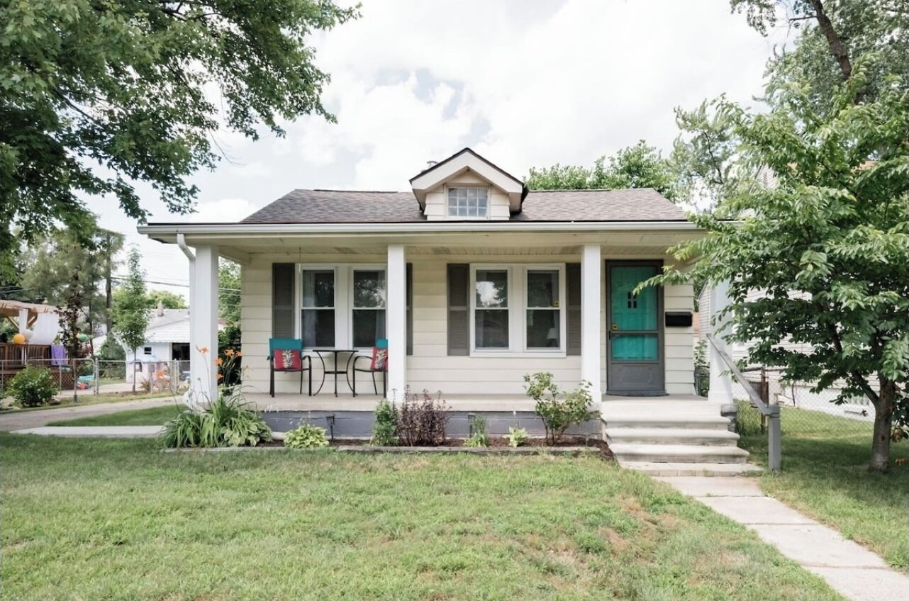 A single-story house with a front porch, a green door, and a small front yard.