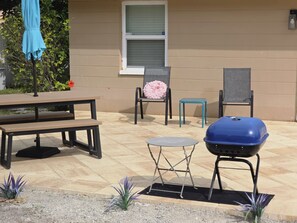 An outdoor patio with a barbecue grill, a table, and chairs. - Newly renovated outdoor space, hot tub, fire pit,minutes from the beach. (Largo)