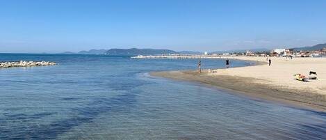 A beach with clear water, a sandy shore, and a few people.